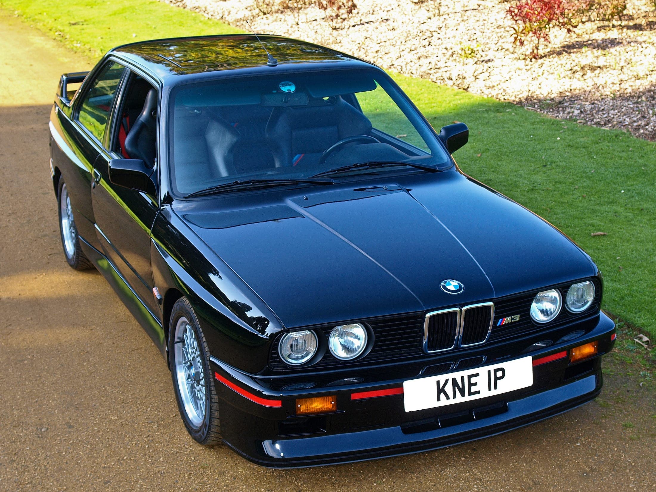 BMW M3 E30 Sport Evolution negro con los filetes rojos del faldón, vista de tres cuartos delantera
