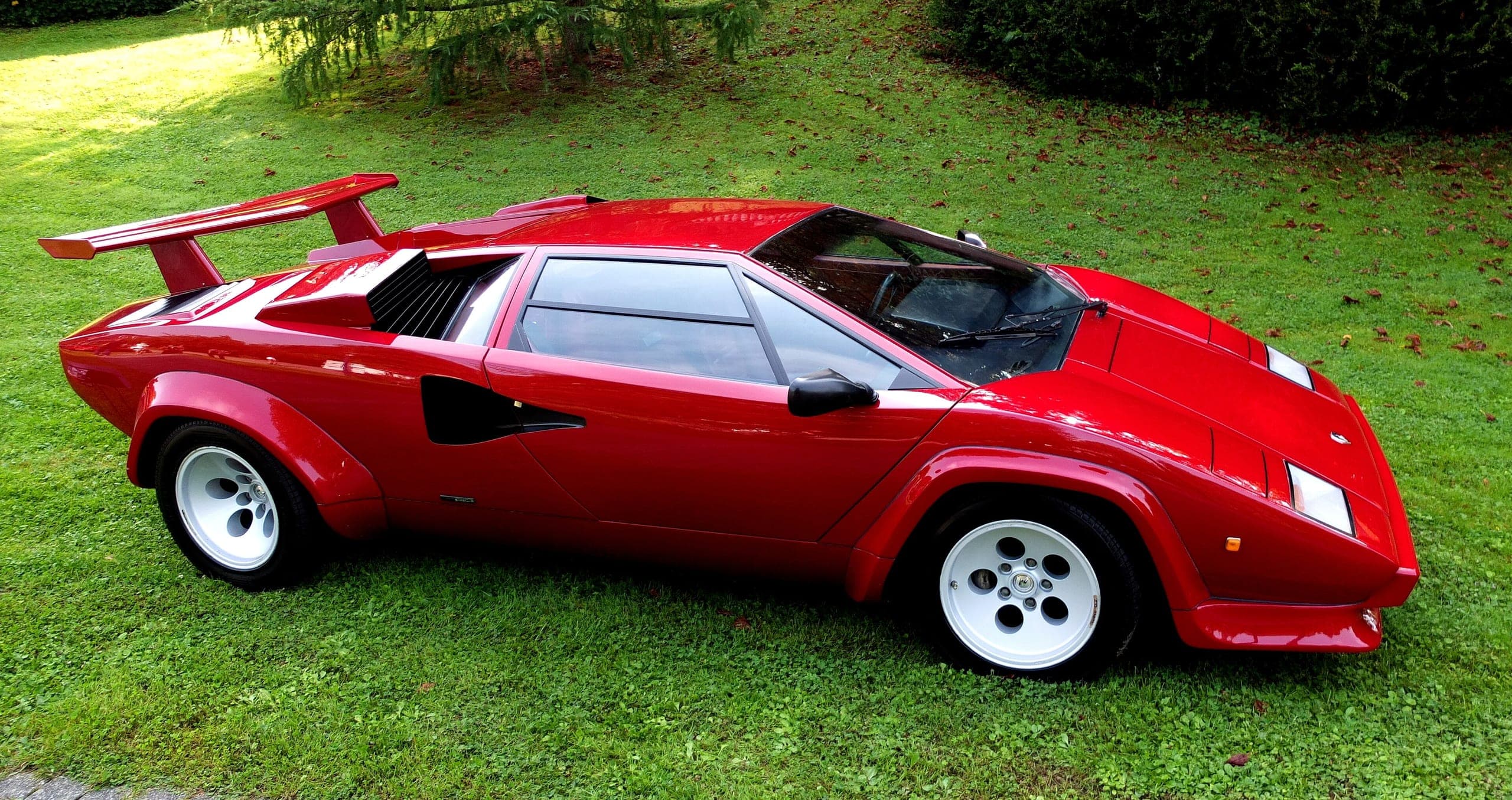 Lamborghini Countach LP500 S roja, vista lateral elevada, con los pasos de rueda ensanchados y el alerón trasero